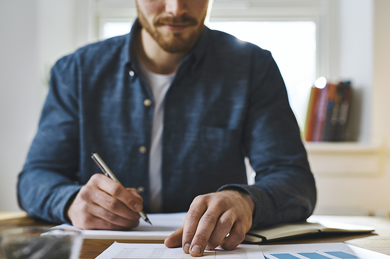 Man writing in notebook at table