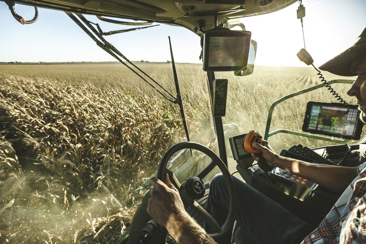 Farmer driving tractor in corn field 