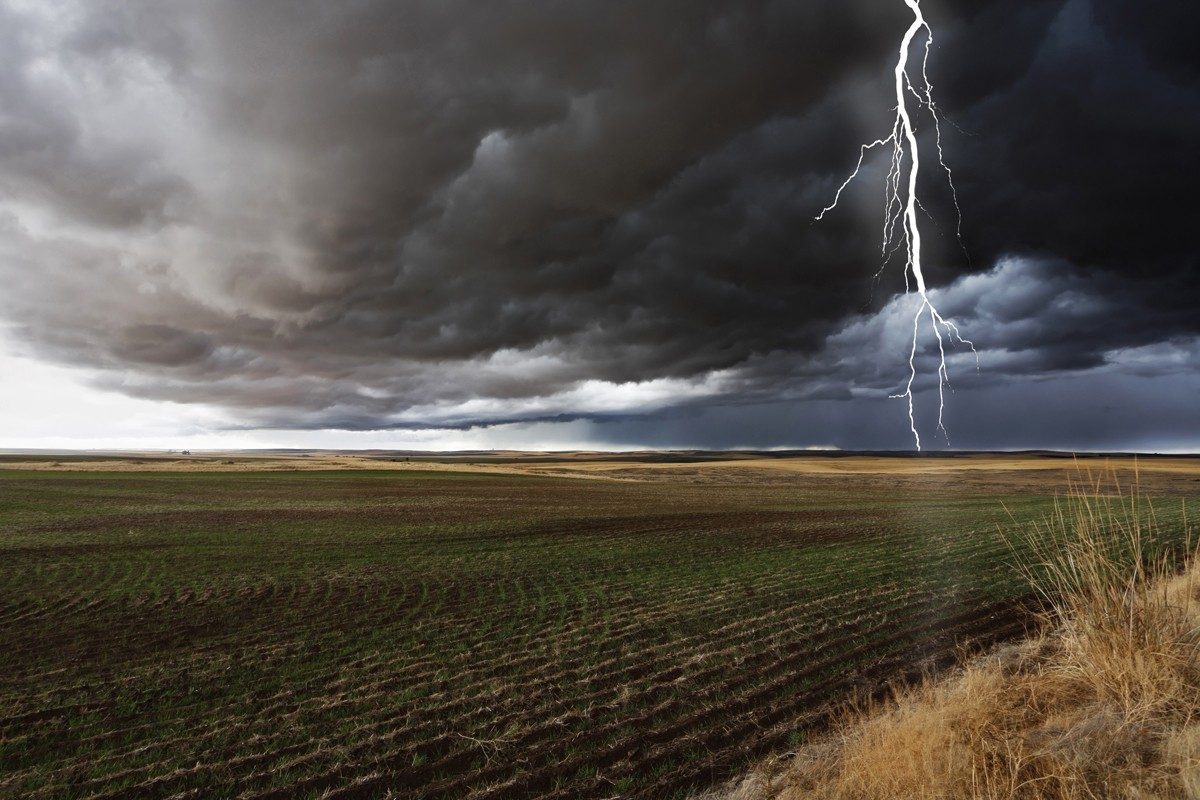 Lightning bolt striking in farm field during storm
