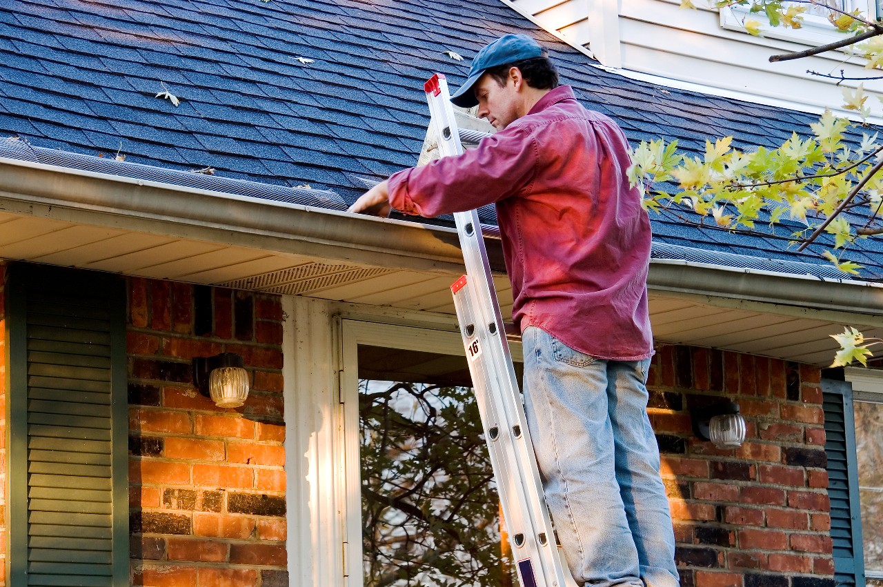 Man cleaning gutters on his home 