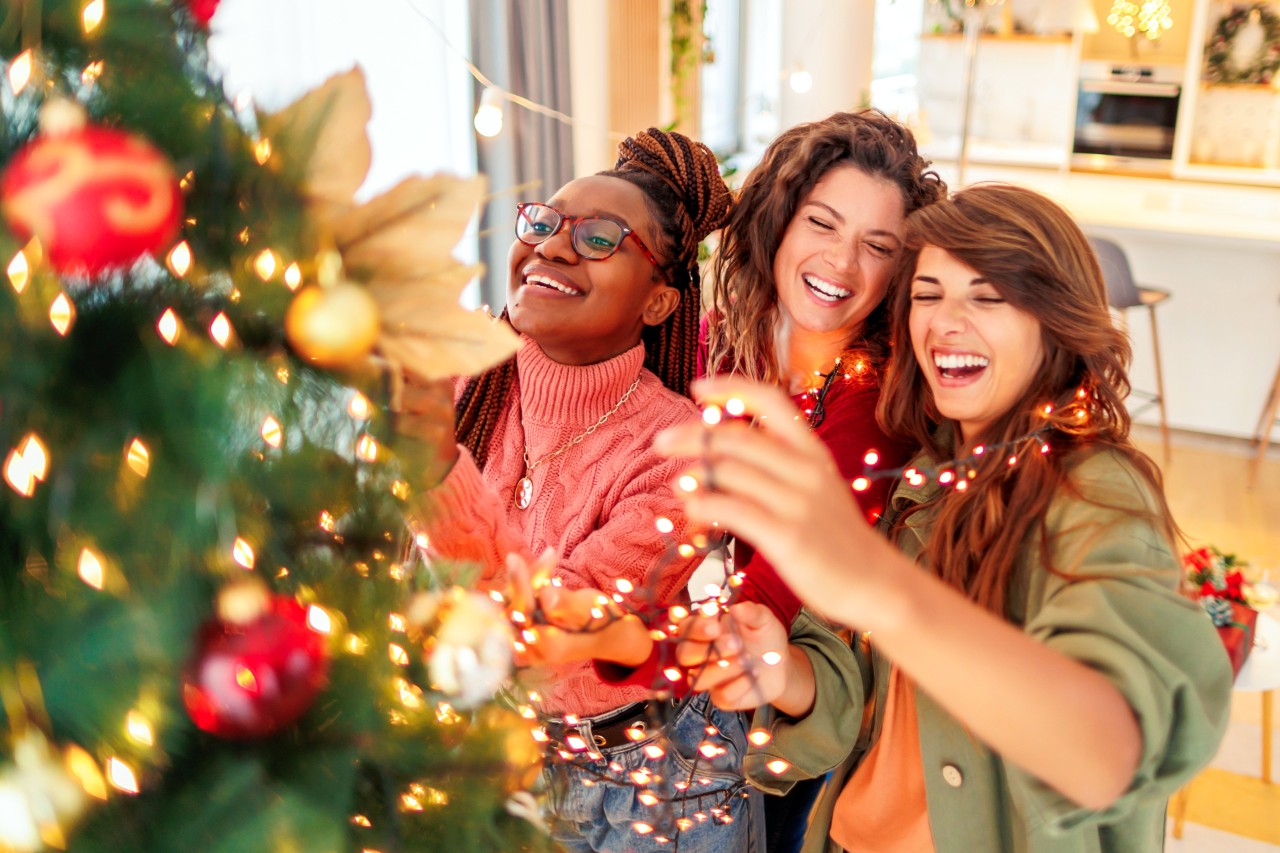 Three girlfriends decorating Christmas tree