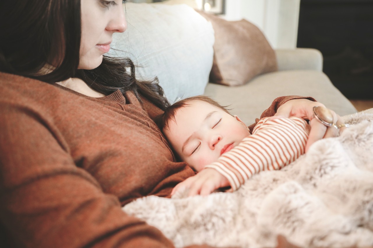 Mother on couch holding sleeping baby