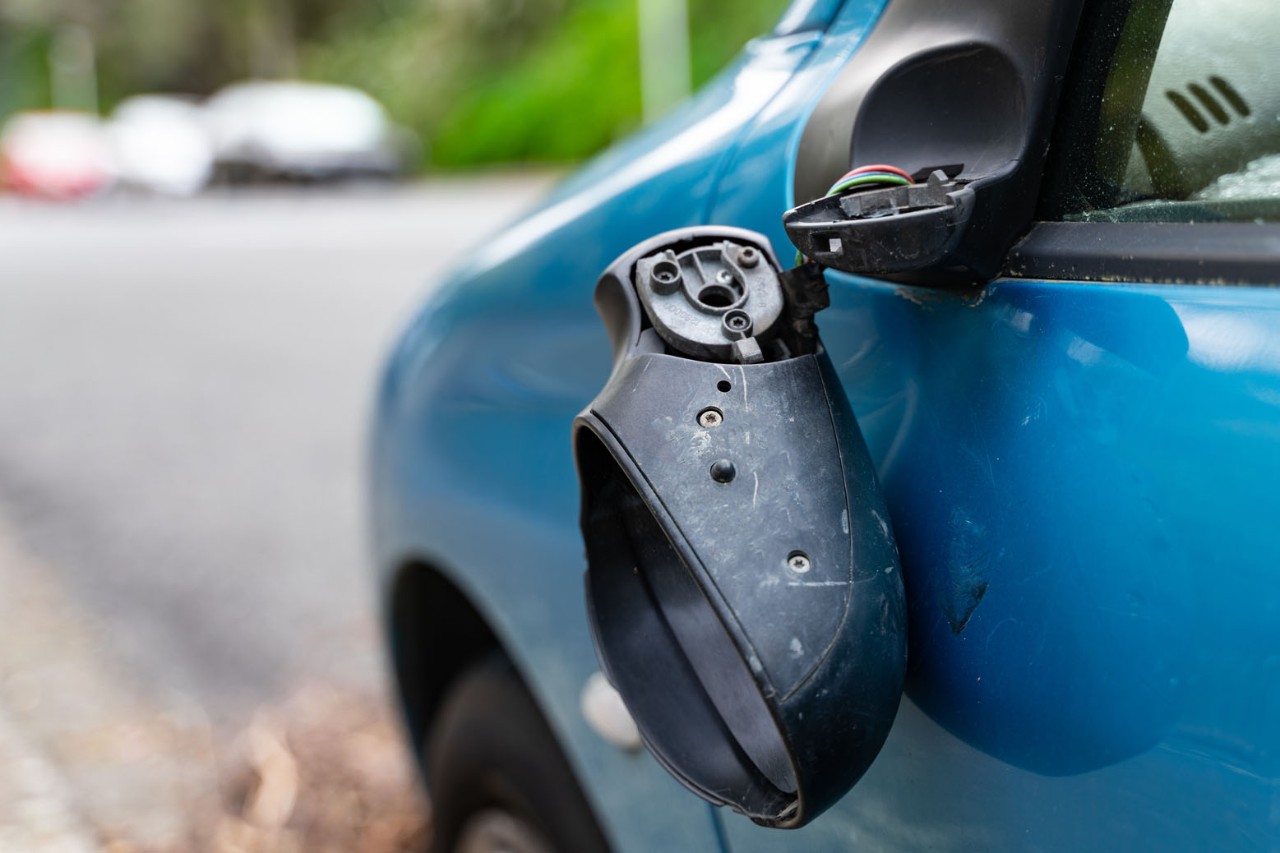 Damaged side mirror on blue car.