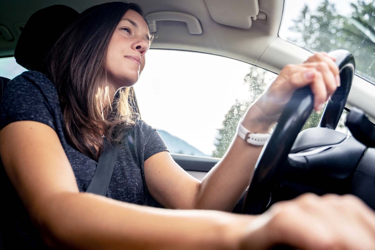 Young woman driving a car on a sunny day.