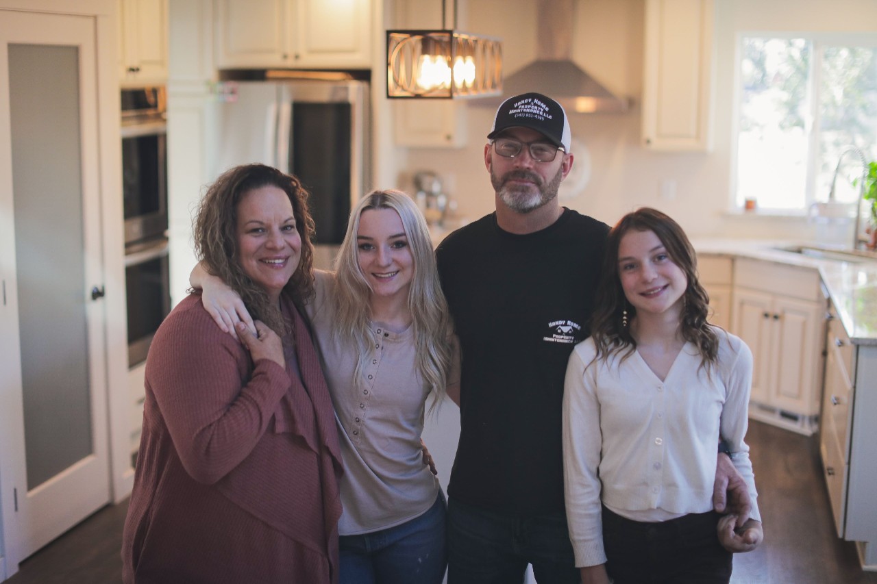 Family in their new kitchen after rebuilding following a wildfire