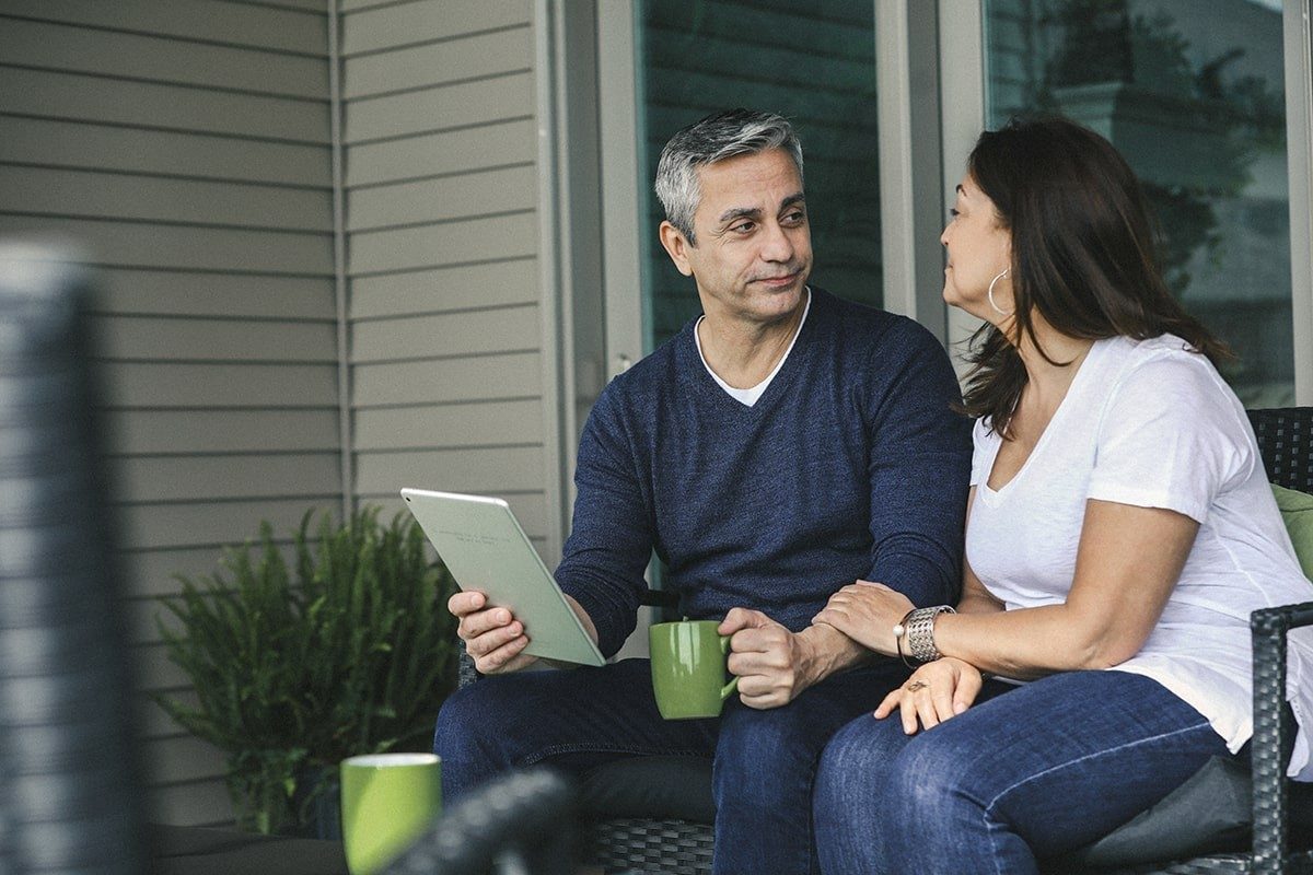 Couple sitting on porch furniture with tablet