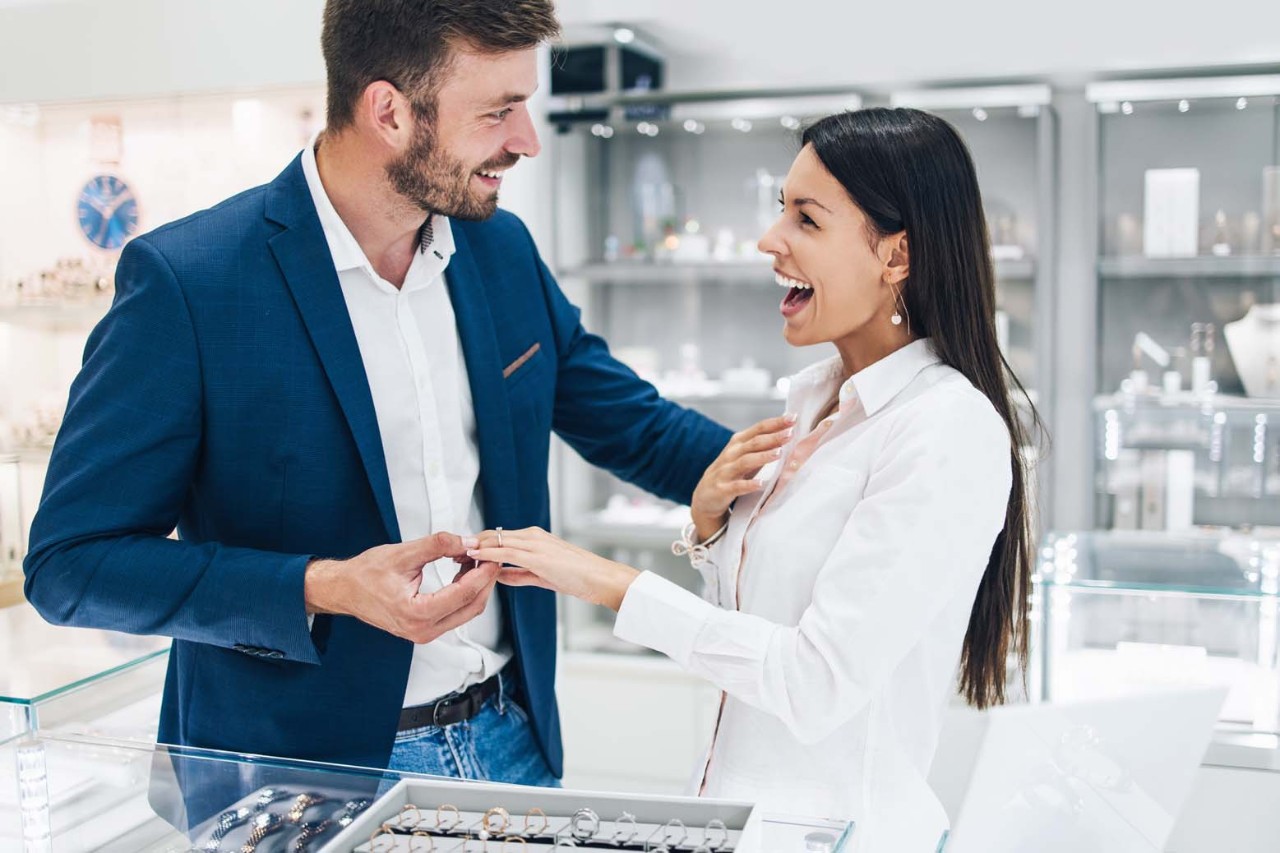 Young couple selecting engagement ring at jewelry store