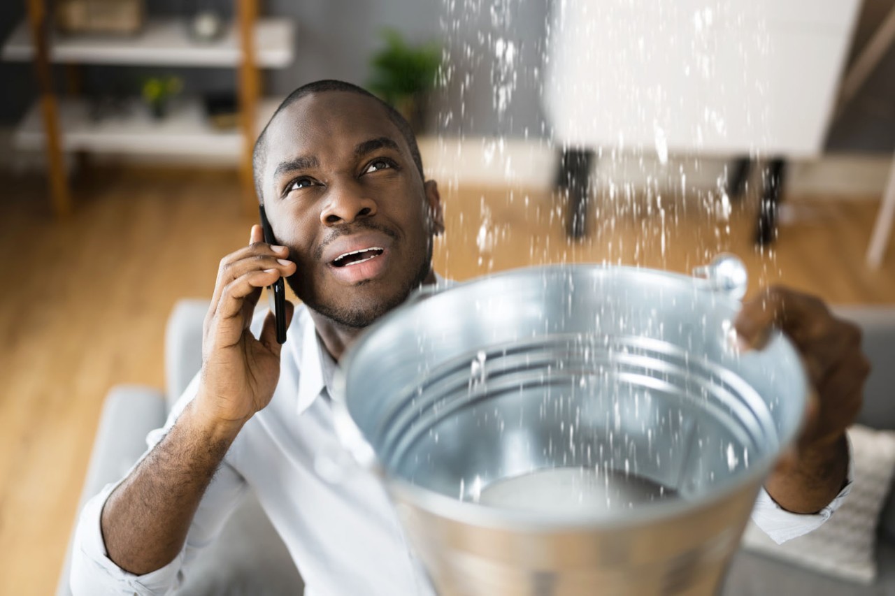 Man holding bucket up to leak