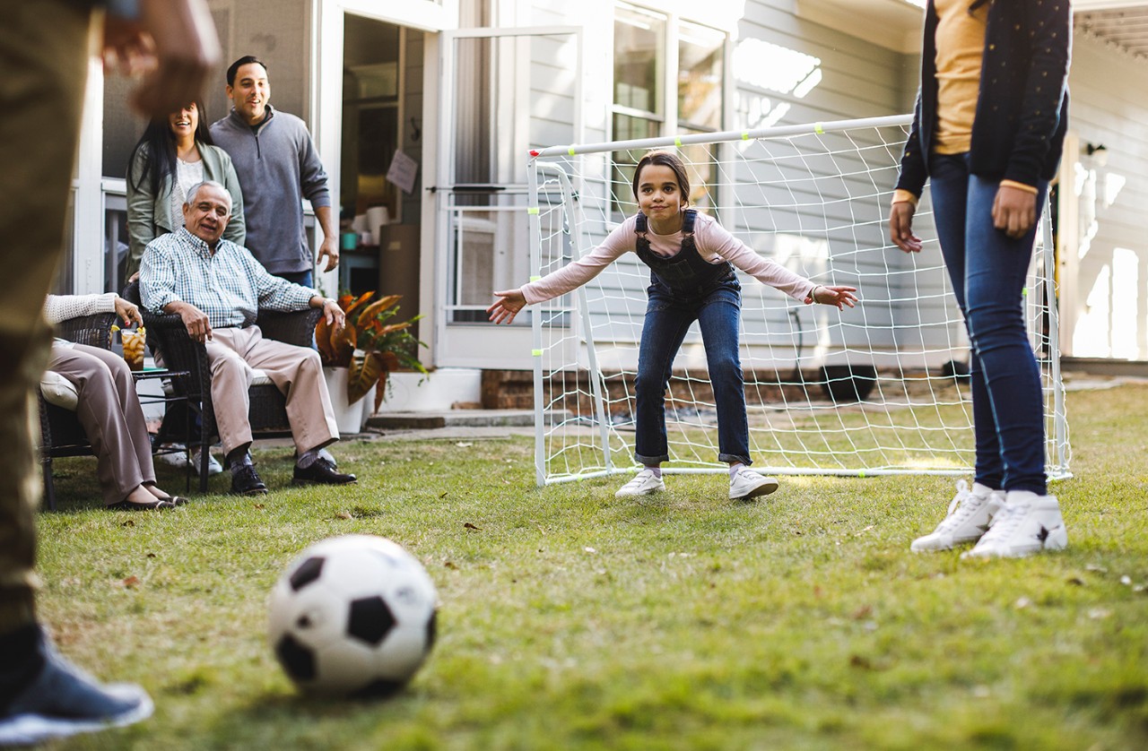 Family with kids playing soccer in their yard