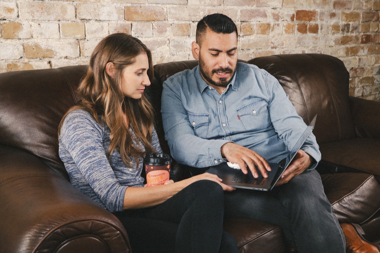 Couple sitting on couch reviewing finances