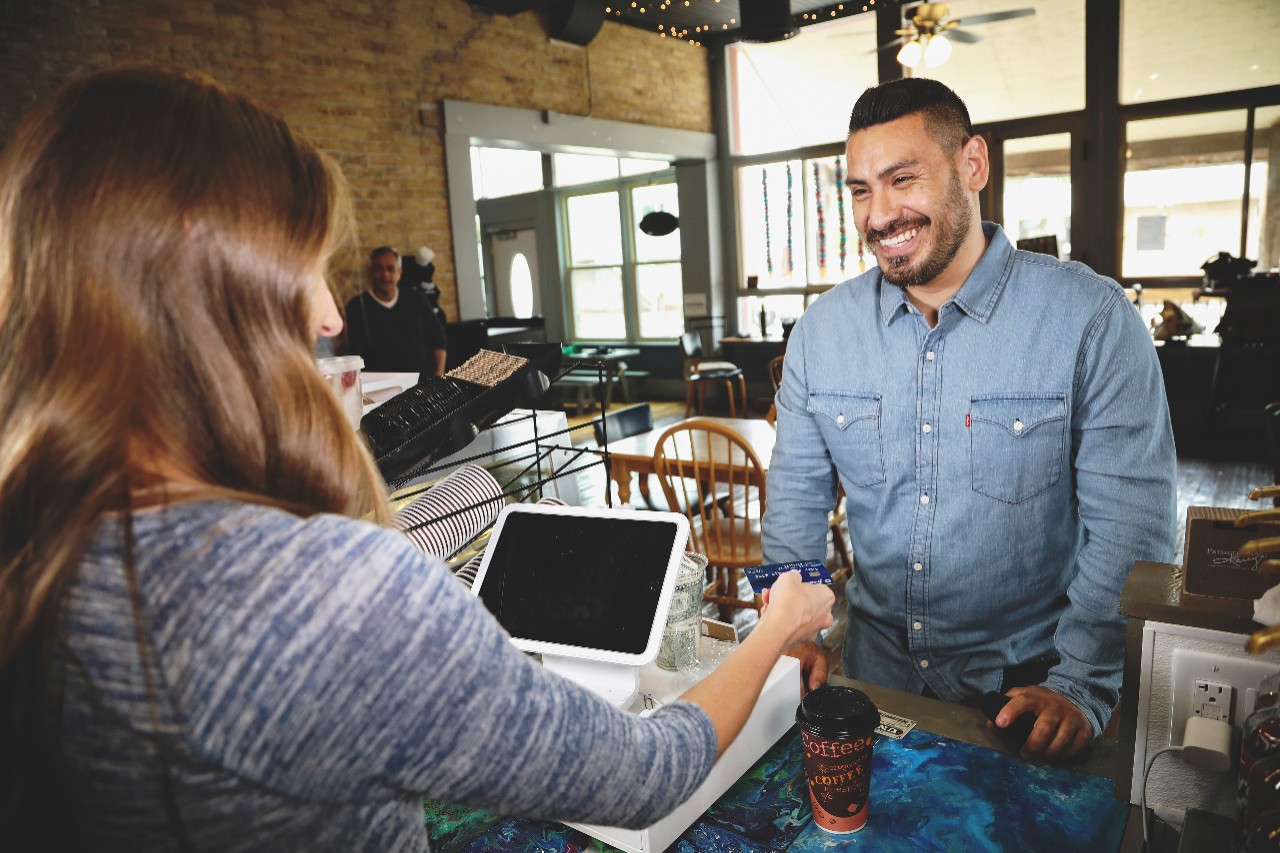 Hispanic male buying coffee with credit/debit card